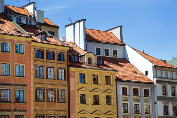 Row of colorful historic buildings in Warsaw, Poland, under a bright blue sky.