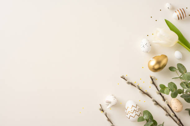 istock Easter themed image with golden eggs, white tulip, and natural decorations on light backdrop 2200546823