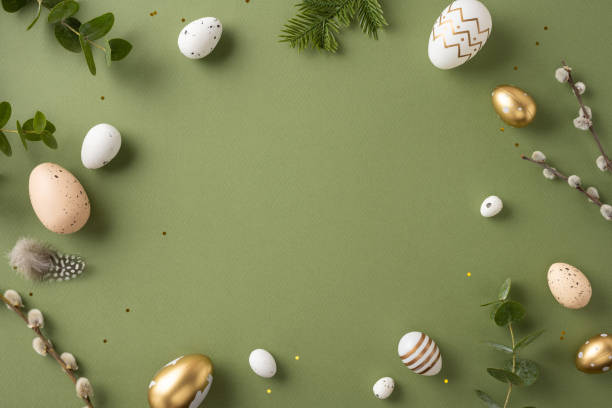 Easter-themed flat lay with decorated eggs, greenery, and feathers arranged aesthetically on green backdrop