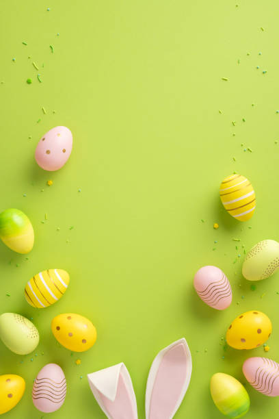 istock Colorful vertical painted Easter eggs and bunny ears arranged on a vibrant green background 2200546869