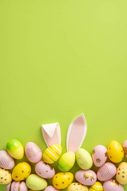 istock Colorful vertical painted Easter eggs and playful bunny ears on a vibrant green background creating a festive spring composition 2200546878