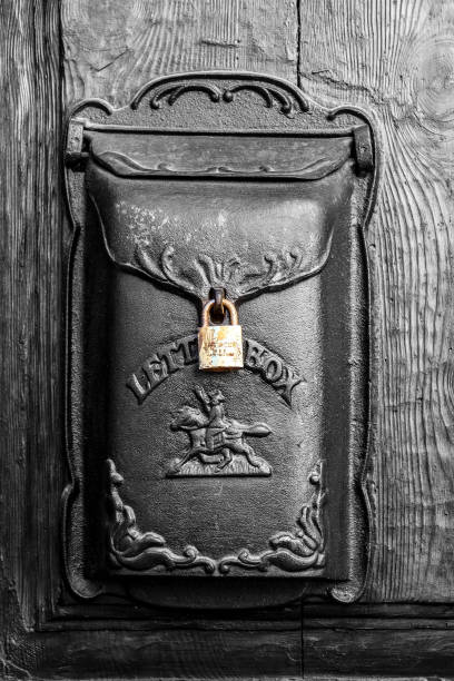 Alicante, Spain- February 8, 2025: Old black metal mailbox with golden lock on wooden door