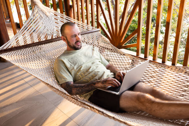 istock Smiling man in hammock with laptop 2200550848
