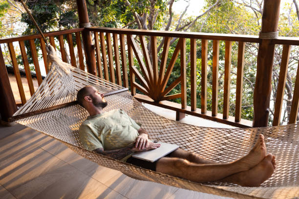 Caucasian man in hammock at a tropical destination working remote