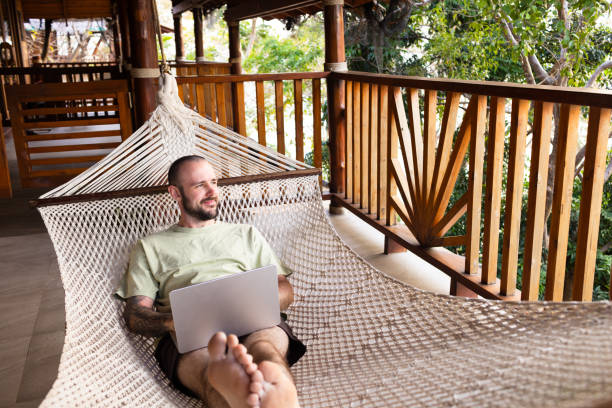 istock Smiling man in hammock with laptop 2200550872