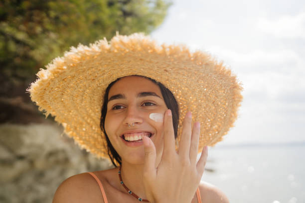 istock Young woman applying sunscreen on her face while at the beach 2200551203