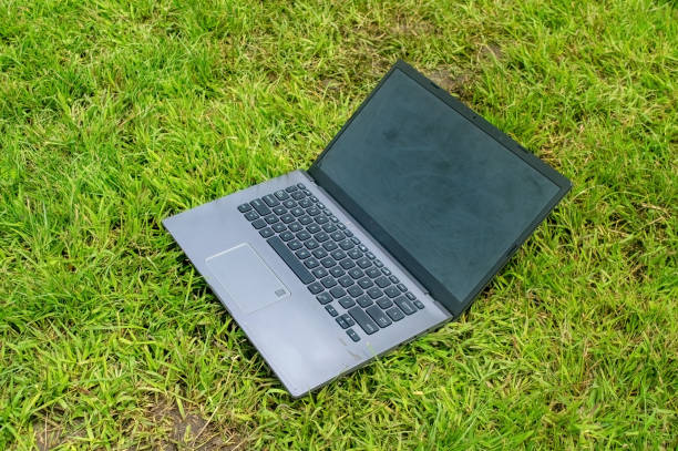 istock A laptop with a black screen and grey keyboard is placed on green grass outdoors. This image is ideal for themes related to remote work, outdoor computing, or digital nomad lifestyle 2200551341