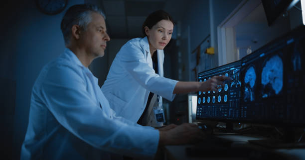 istock In Control Room Doctor and Radiologist Discuss Diagnosis while Watching Procedure and Monitors Showing Brain Scans Results. Patient Undergoes MRI or CT Scan Process in High-Tech Medical Facility 2200552972