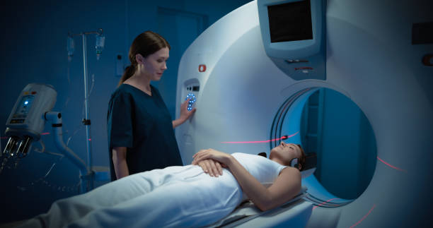 istock Professional Doctor Conducts Emergency Check Up Procedure with Advanced Medical Technologies. In Medical Laboratory, Radiologist Controls MRI or CT or PET Scan with Female Patient Undergoing Procedure 2200553225