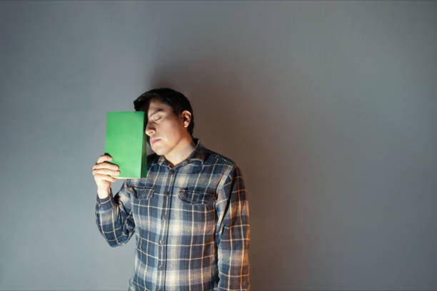 Thoughtful Young Man Reflecting on Poetry Day with Green Notebook in Hand
