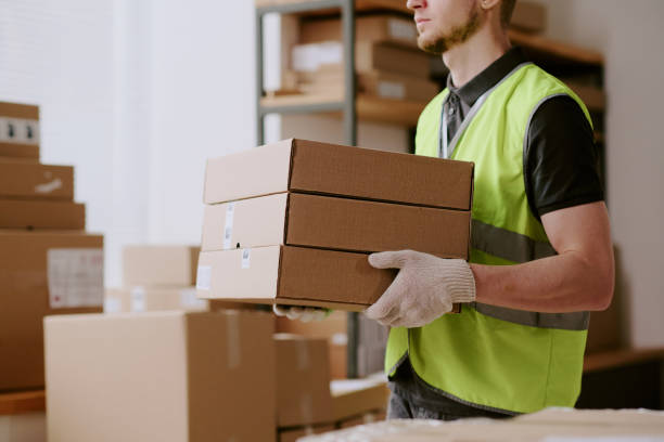 istock Man Holding Boxes in Warehouse Wearing Safety Vest 2200556388