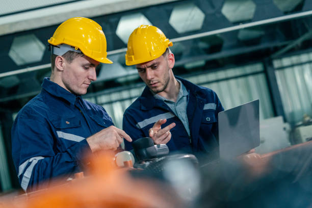 istock Two engineers collaborate on machinery inspection in a factory setting during daytime 2200561821