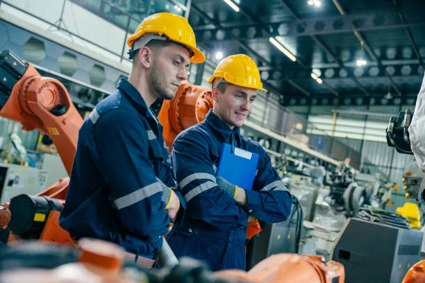 istock Workers discussing operations at a modern manufacturing facility with robotic arms in use 2200562292