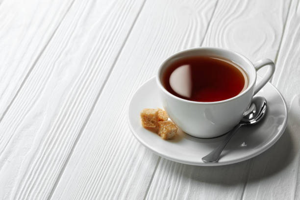 istock black tea in cup on saucer with spoon and sugar cubes on white wooden table 2200565708