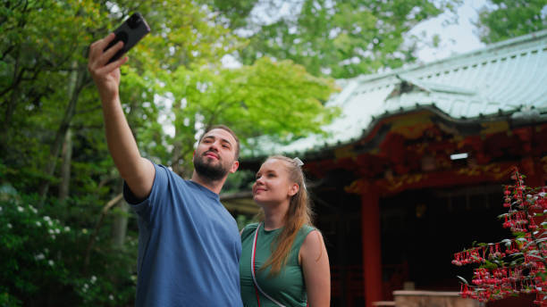 istock Young Couple Visiting Japanese Shrine and Enjoying Taking Selfies 2200570835