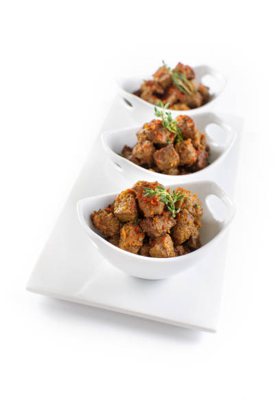 Three small porcelain bowls filled with crispy, golden-brown fried liver, arranged on a clean white surface for a minimalist presentation.