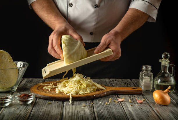 istock In a cozy kitchen, a chef expertly shreds fresh cabbage using a mandoline. Surrounding ingredients include onions, garlic, and spices, hinting at a flavorful recipe in progress 2200571013