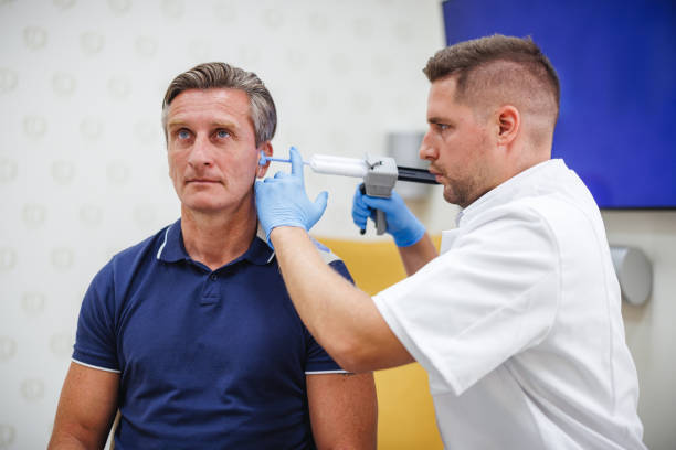 Asian male Otolaryngologist examining elderly man ears using an otoscope in Otolaryngology at clinic