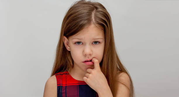 istock Shy child holding finger in mouth 2200575644