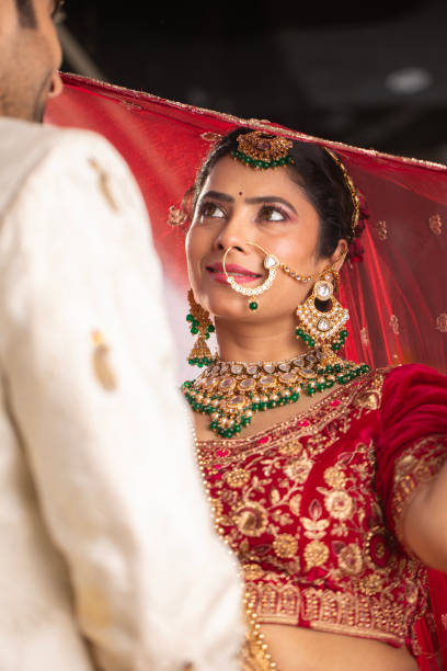 istock Bride looking at groom holding her red veil in wedding ceremony 2200576011