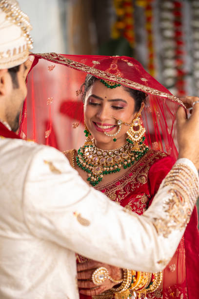 istock Bride looking at groom holding her red veil in wedding ceremony 2200576049