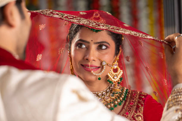 istock Bride looking at groom holding her red veil in wedding ceremony 2200576117