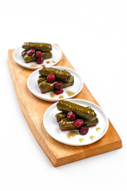 Traditional Turkish-style grape leaf dolma, placed in rows on a serving plate, with sour cherries.