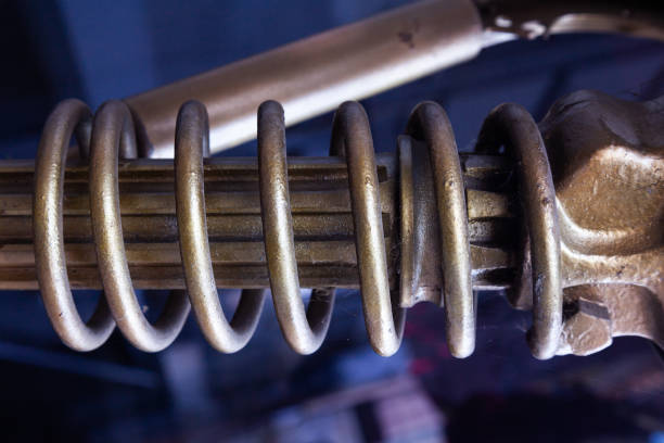 Steel mechanical part with a large spring, painted with golden paint.