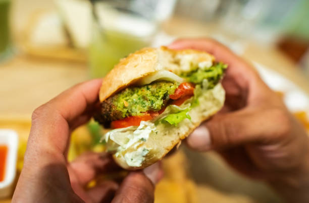 istock Man with falafel burger in a vegan cafe 2200580522