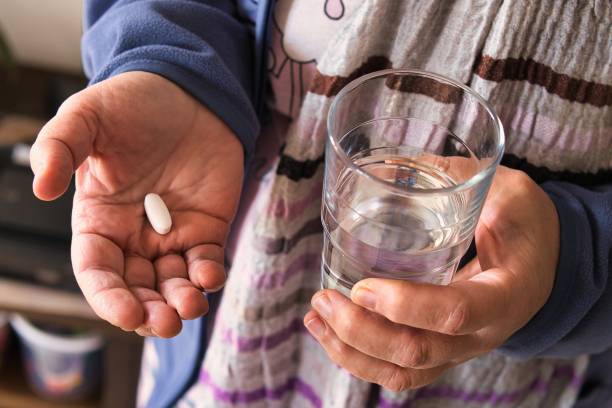 istock Hands holding pill and water glass. 2200584400
