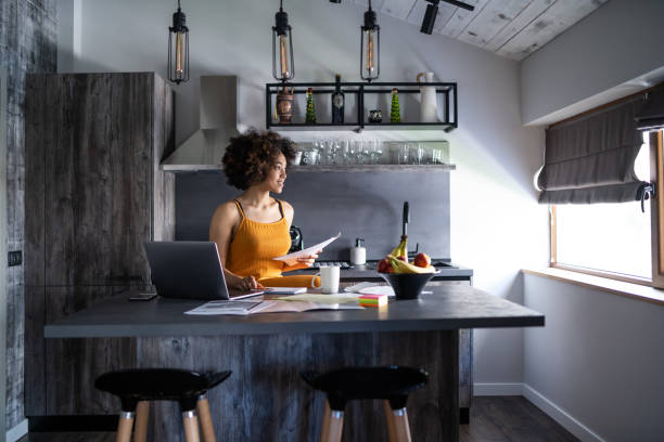 istock Afro woman works diligently with documents in her kitchen 2200586931