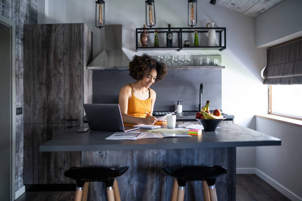 istock Afro woman works diligently with documents in her kitchen 2200586939