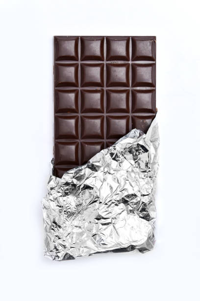 istock Chocolate bar partially wrapped in silver foil on a white background. The rich, dark brown chocolate contrasts with the shiny metallic wrapper. 2200588549