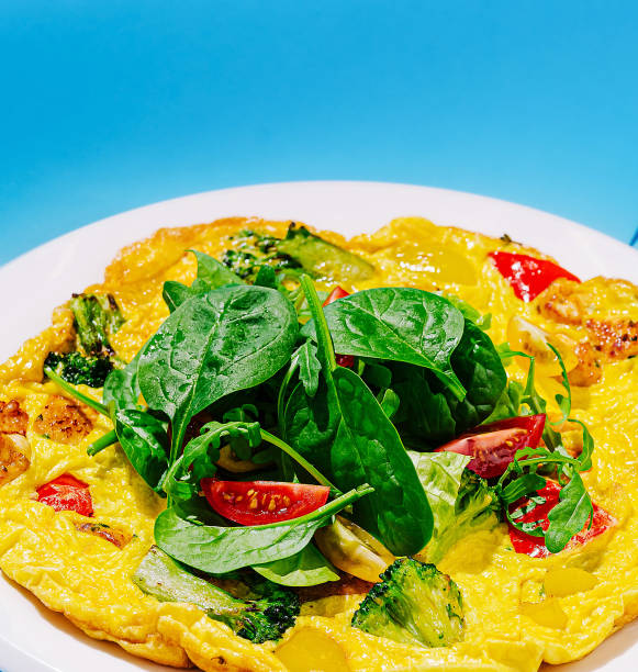 Delicious vegetable omelette garnished with fresh spinach on a bright blue background