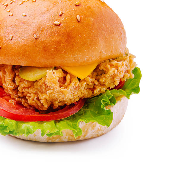 istock Crispy fried chicken sandwich with lettuce, tomato, and cheese on a sesame seed bun served on a white background 2200589267