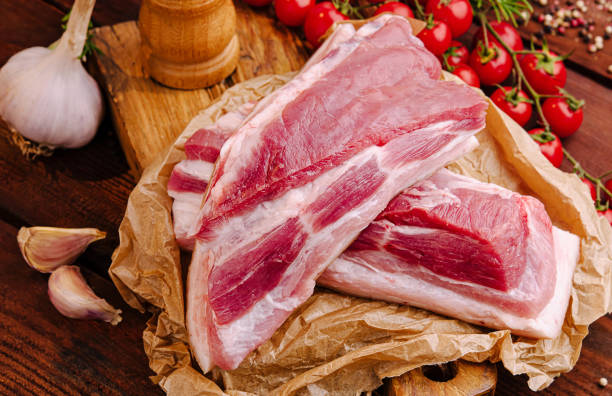 istock Fresh pork with garlic and cherry tomatoes on a wooden board 2200590452