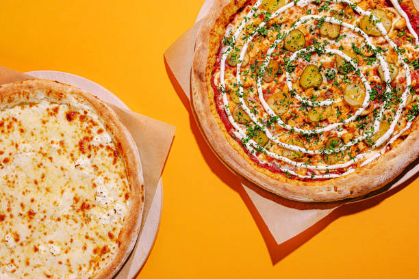 istock Delicious pizzas displayed on a vibrant orange background, showcasing cheese and unique toppings with fresh ingredients 2200590736