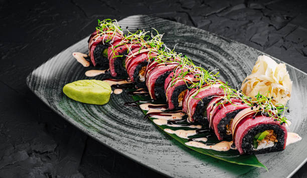 Delicious sushi roll presented elegantly on a dark plate with wasabi and pickled ginger