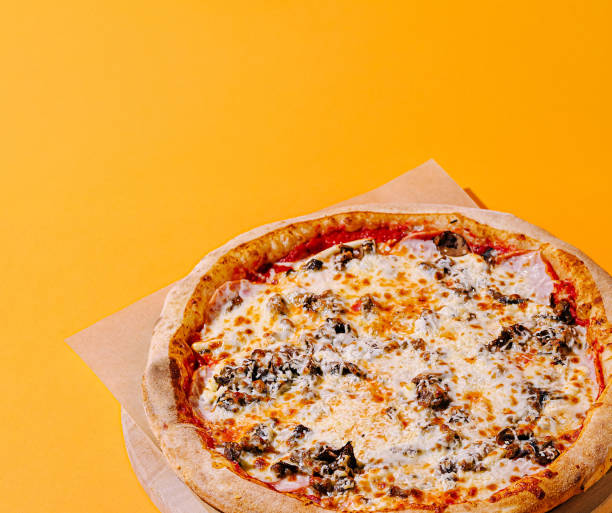 istock Freshly made pizza with a golden crust on an orange background ready to be enjoyed 2200593161