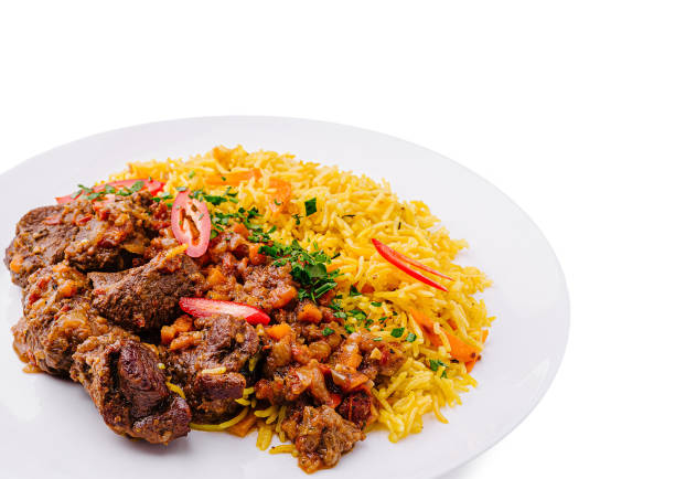 A delicious meat dish is presented alongside a vibrant serving of spiced rice, garnished with fresh vegetables. This colorful plate showcases a blend of flavors and aromas.