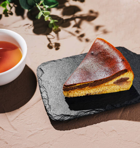 istock Delicious Basque cheesecake slice on a slate plate with tea and greenery in a natural setting 2200593701