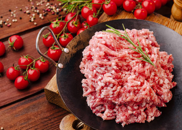 istock Freshly minced meat on a wooden table surrounded by spices and tomatoes ready for cooking 2200593830
