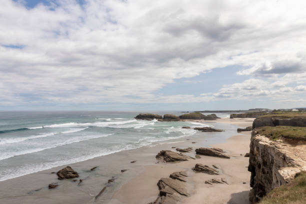 istock A scenic coastal landscape featuring a sandy beach, rugged rock formations, and ocean waves under a partly cloudy sky. A peaceful and natural seaside view 2200598848