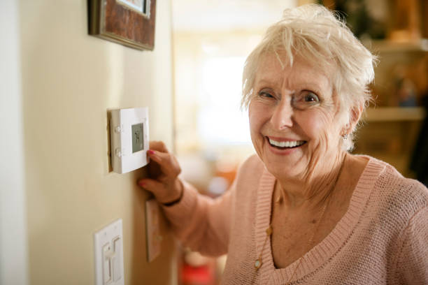 istock senior lady posing at home portrait close to a window using thermostat 2200600704