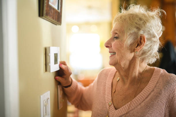 istock senior lady posing at home portrait close to a window using thermostat 2200600707