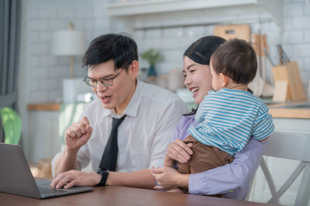 istock Parents enjoy family time while teaching their child using a laptop at home in a bright living room 2200602454