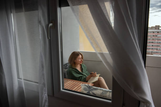 istock Woman Writing in Notebook on Cozy Balcony 2200611741