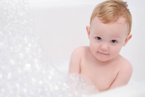Little boy playing in a bathtub with soap suds