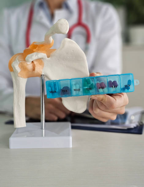 istock Medical professional demonstrates a shoulder joint model while holding a weekly pill organizer during patient consultation concept 2200612495