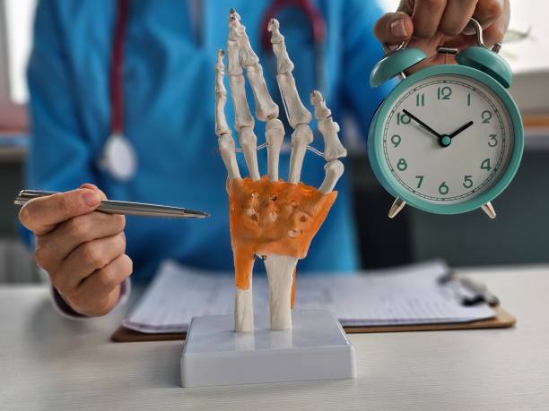 istock Medical professional examines skeletal hand model while holding clock in clinic during consultation concept 2200612552